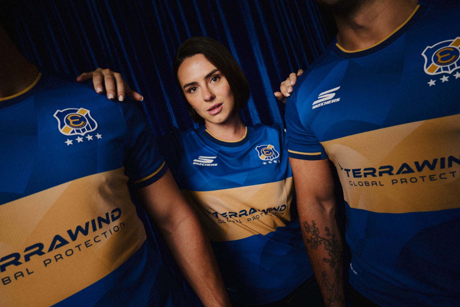 Jugadora entre dos jugadores con la camiseta oficial de Everton