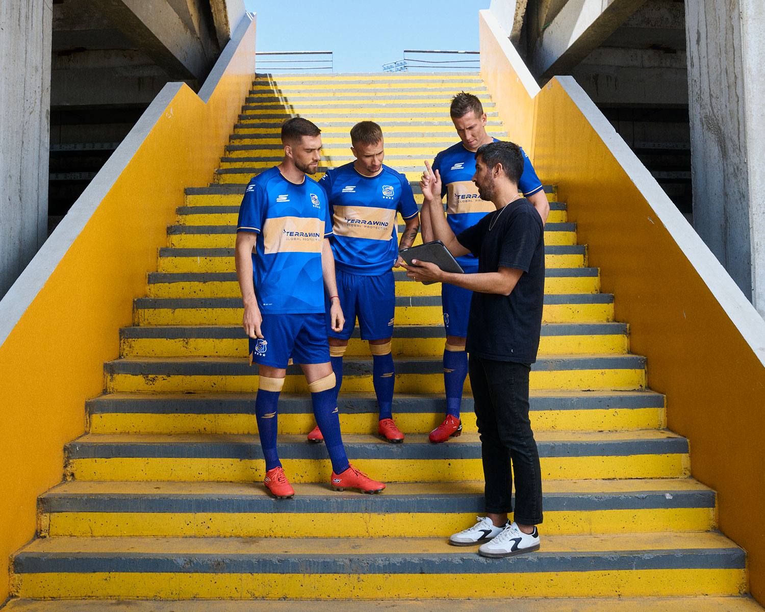 Andrés dirigiendo a tres futbolistas en la escalera de un estadio